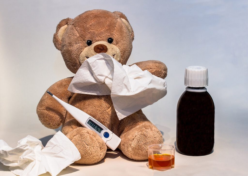Bild einen Stoffbären mit Taschetuch vor der Nase und Fieberthermometer in der Pfote, daneben eine Apothekenflasche